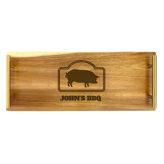 A large rectangular wooden serving tray with laser-engraved design including an illustration of a pig and the text 'JOHN'S BBQ'.