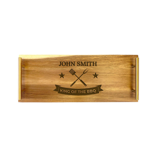 A rectangular wooden serving tray with 'KING OF THE BBQ' text and an engraved design of a chef's tool on the front.