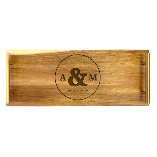 A wooden serving tray with circle initials engraved on it, indicating a personalized touch.